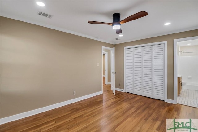 unfurnished bedroom featuring wood-type flooring, connected bathroom, ceiling fan, and a closet