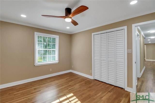 unfurnished bedroom featuring crown molding, light hardwood / wood-style flooring, a closet, and ceiling fan