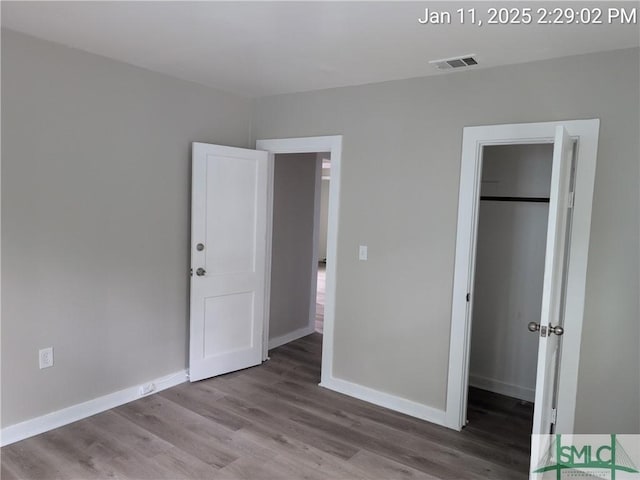 unfurnished bedroom featuring a walk in closet, wood-type flooring, and a closet