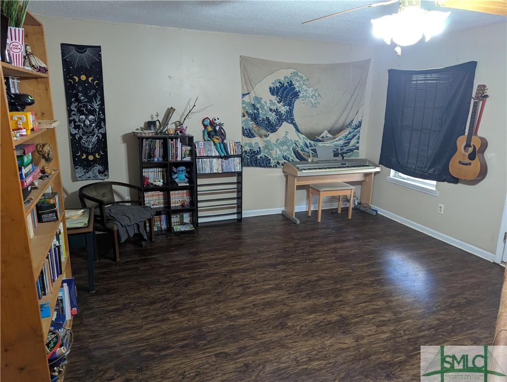 misc room with ceiling fan, dark hardwood / wood-style floors, and a textured ceiling