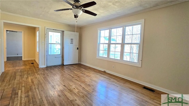 interior space featuring hardwood / wood-style flooring, ceiling fan, ornamental molding, and a textured ceiling