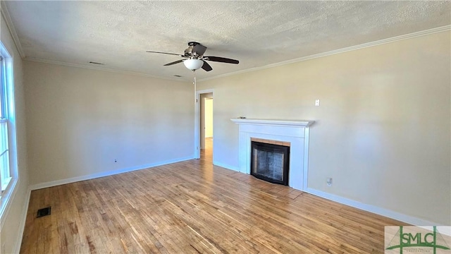 unfurnished living room with a fireplace, visible vents, ceiling fan, and wood finished floors