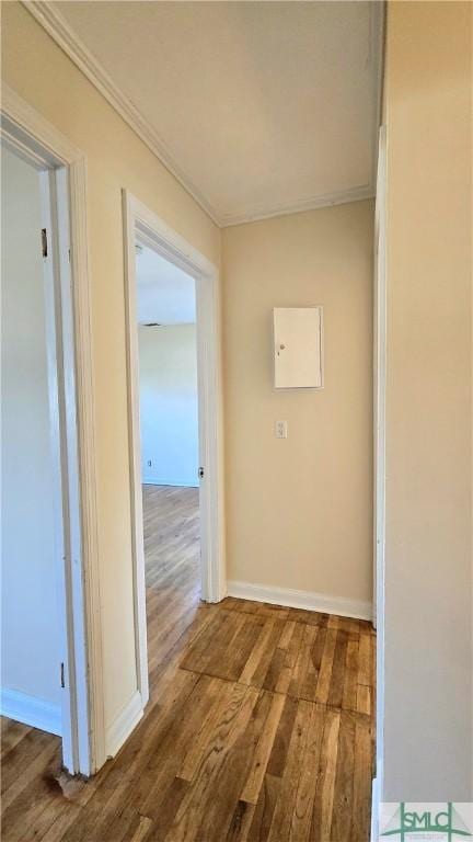 hall featuring baseboards, crown molding, and wood finished floors