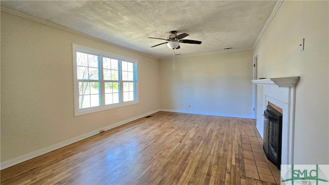 unfurnished living room featuring a fireplace, a textured ceiling, crown molding, a ceiling fan, and wood finished floors