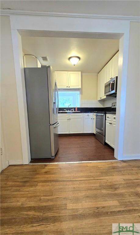 kitchen with visible vents, dark countertops, dark wood finished floors, white cabinetry, and stainless steel appliances