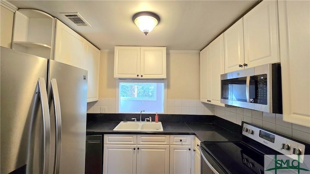 kitchen with tasteful backsplash, appliances with stainless steel finishes, sink, and white cabinets