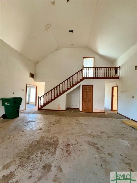 unfurnished living room featuring high vaulted ceiling