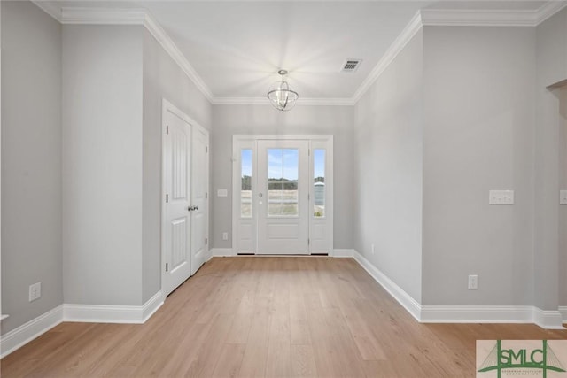 foyer entrance with an inviting chandelier, ornamental molding, and light wood-type flooring