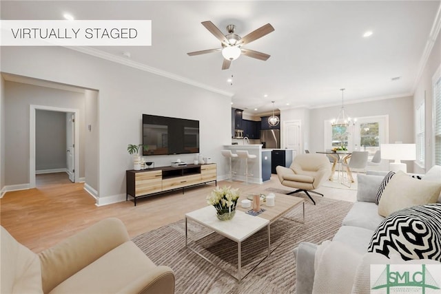 living room with ceiling fan with notable chandelier, ornamental molding, and light hardwood / wood-style floors