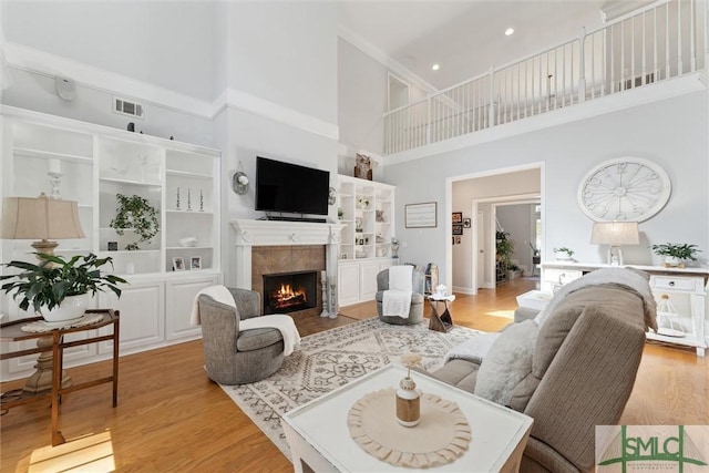 living room featuring a towering ceiling, a fireplace, and light hardwood / wood-style floors