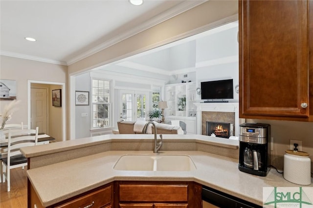 kitchen featuring ornamental molding, dishwasher, sink, and light hardwood / wood-style flooring