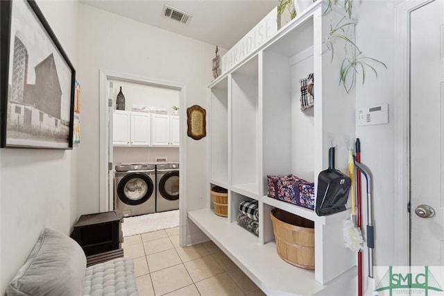 laundry area featuring light tile patterned flooring, cabinets, and washing machine and clothes dryer