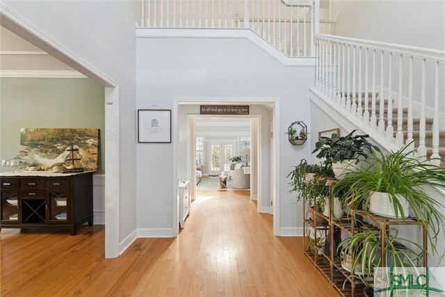 hallway with a high ceiling and light hardwood / wood-style flooring