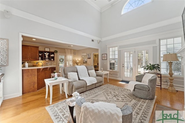 living room featuring ornamental molding, a wealth of natural light, and light hardwood / wood-style floors