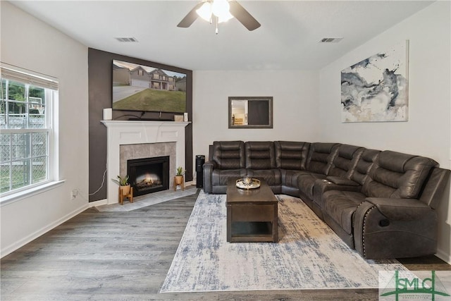 living room featuring a tiled fireplace, hardwood / wood-style floors, and ceiling fan