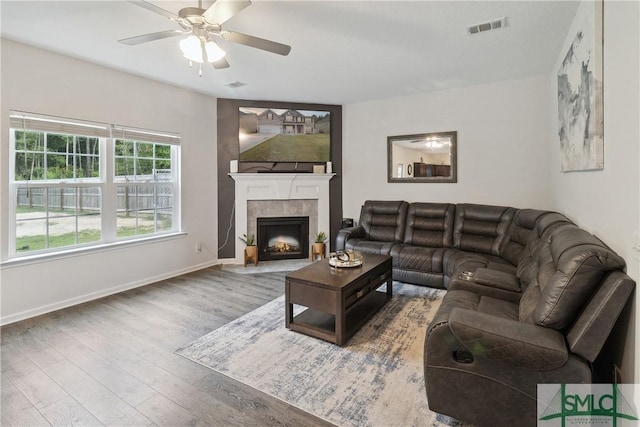 living room featuring a tile fireplace, wood-type flooring, and ceiling fan