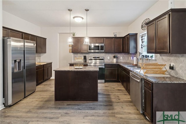 kitchen with sink, dark brown cabinets, a kitchen island, pendant lighting, and stainless steel appliances