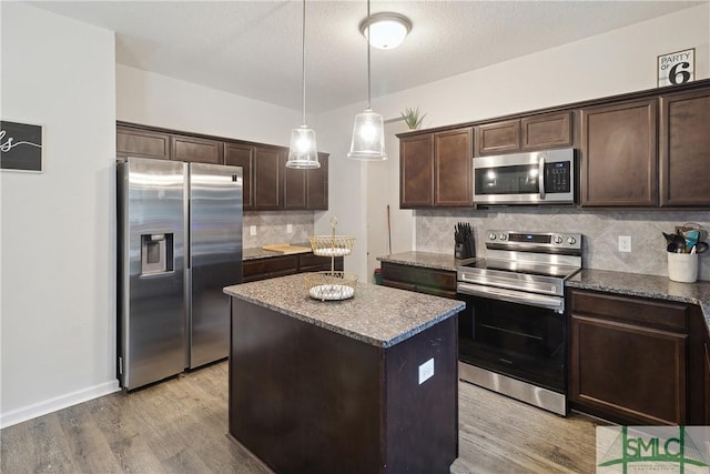 kitchen with dark brown cabinetry, tasteful backsplash, a center island, hanging light fixtures, and appliances with stainless steel finishes