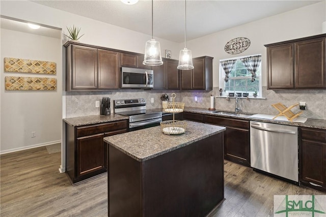 kitchen featuring sink, a center island, dark brown cabinets, appliances with stainless steel finishes, and pendant lighting