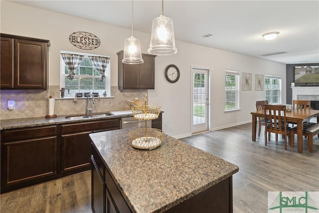 kitchen featuring sink, dark hardwood / wood-style flooring, decorative backsplash, a center island, and dark brown cabinetry