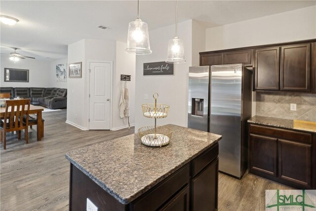 kitchen with stone countertops, a center island, stainless steel fridge with ice dispenser, dark brown cabinets, and light hardwood / wood-style flooring