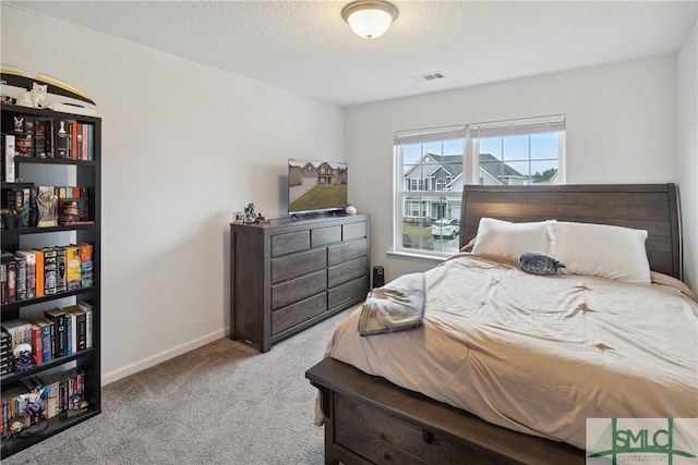 bedroom with light colored carpet and a textured ceiling