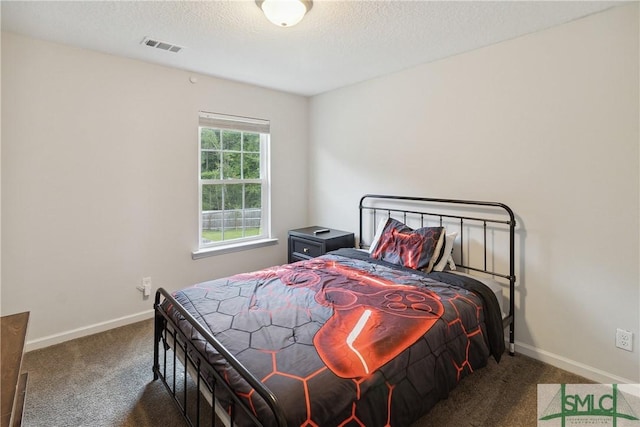 bedroom with a textured ceiling and dark carpet