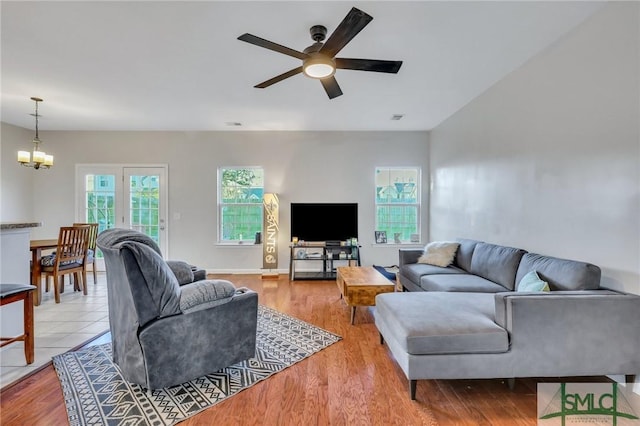 living room featuring visible vents, light wood-style flooring, and ceiling fan with notable chandelier