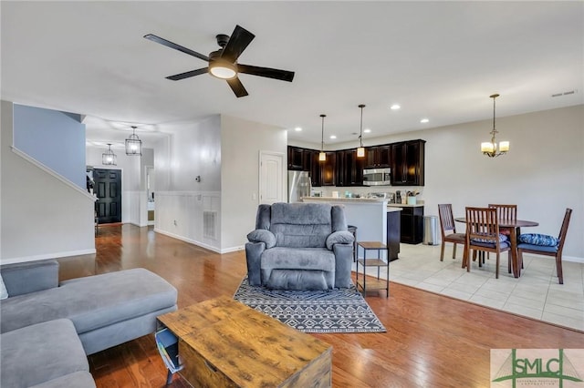 living room with recessed lighting, visible vents, light wood-style flooring, and ceiling fan with notable chandelier