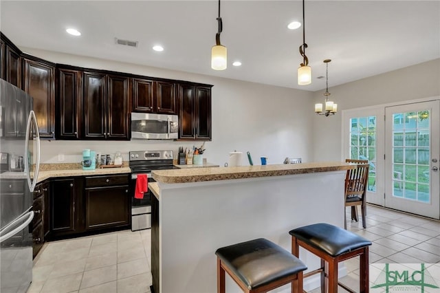 kitchen with a center island, decorative light fixtures, light tile patterned floors, stainless steel appliances, and light countertops