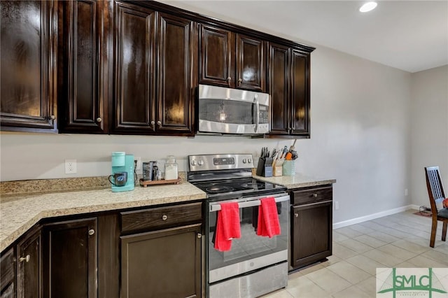 kitchen featuring baseboards, appliances with stainless steel finishes, light countertops, and dark brown cabinets