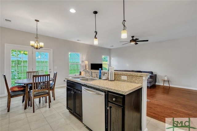 kitchen with a sink, light countertops, hanging light fixtures, dishwasher, and an island with sink