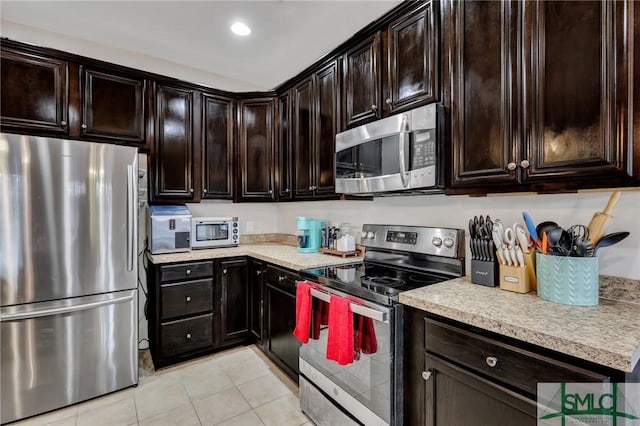 kitchen with stainless steel appliances, light countertops, dark brown cabinets, and light tile patterned flooring