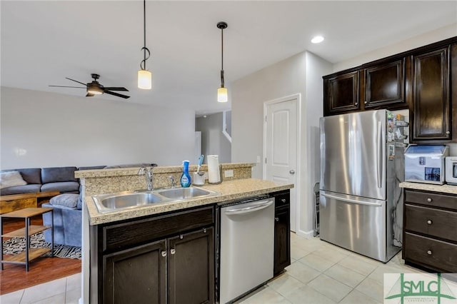 kitchen with decorative light fixtures, light countertops, appliances with stainless steel finishes, open floor plan, and a sink