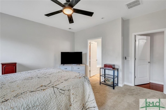 bedroom featuring light colored carpet, visible vents, a ceiling fan, ensuite bath, and baseboards