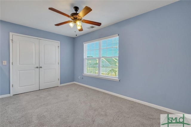 unfurnished bedroom featuring baseboards, visible vents, a closet, and light colored carpet