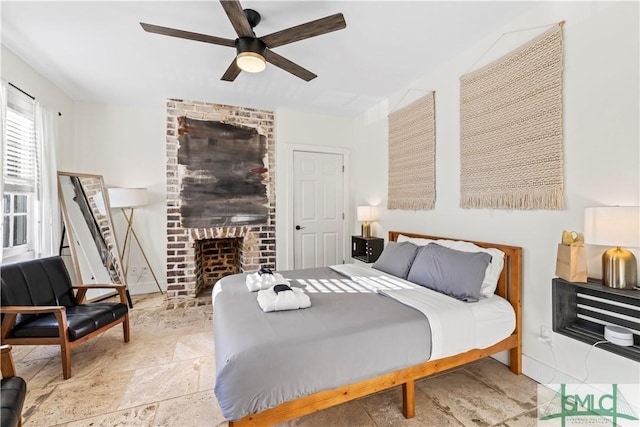 bedroom featuring ceiling fan and a brick fireplace