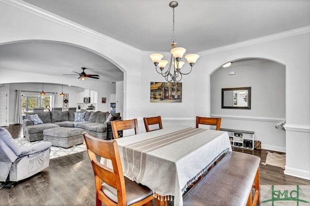 dining space with dark hardwood / wood-style flooring, ceiling fan with notable chandelier, and ornamental molding