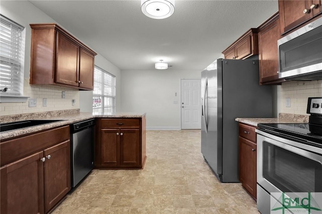 kitchen featuring stainless steel appliances, kitchen peninsula, and backsplash