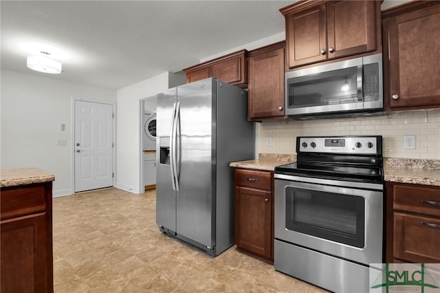 kitchen featuring stainless steel appliances, tasteful backsplash, light stone counters, and washer / clothes dryer