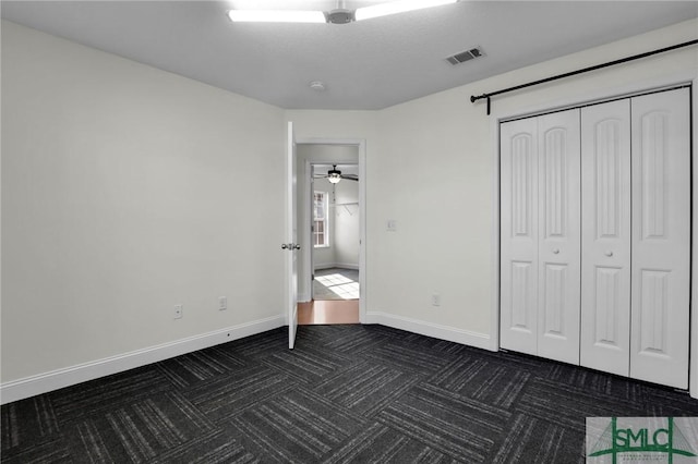 unfurnished bedroom featuring a closet and dark colored carpet