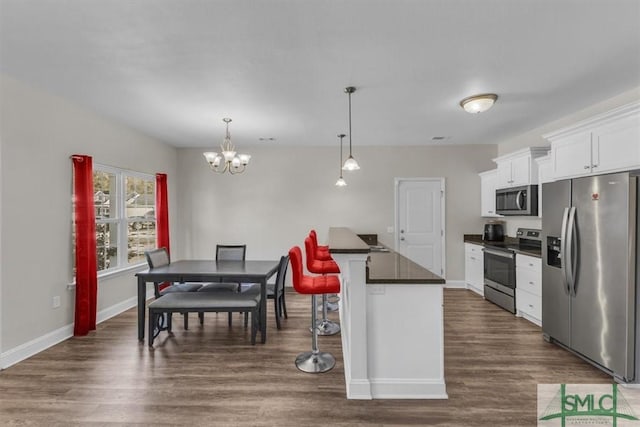 kitchen with a kitchen island, pendant lighting, a breakfast bar area, white cabinets, and stainless steel appliances