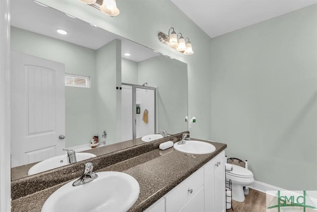 bathroom with wood-type flooring, toilet, vanity, and walk in shower