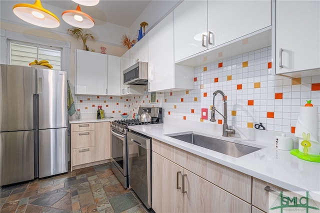 kitchen with appliances with stainless steel finishes, tasteful backsplash, white cabinetry, sink, and light brown cabinets