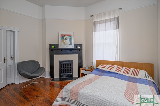 bedroom featuring dark hardwood / wood-style flooring and a fireplace