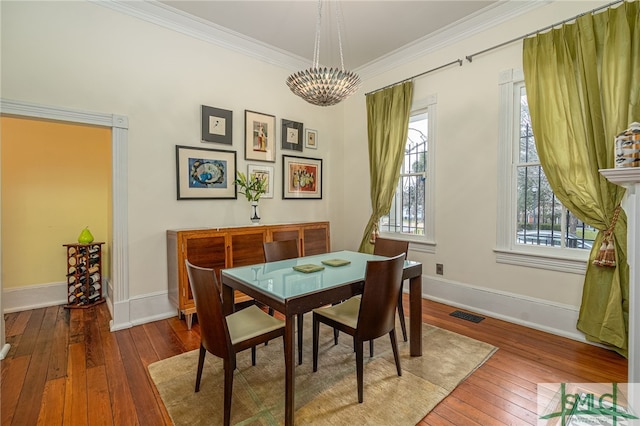 dining space with ornamental molding, wood-type flooring, and a notable chandelier