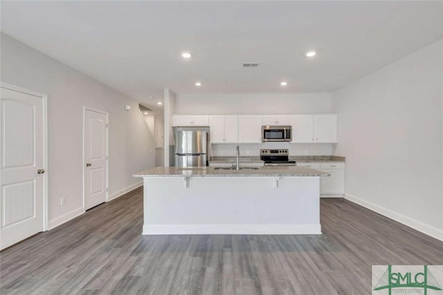 kitchen featuring stainless steel appliances, sink, a kitchen island with sink, and white cabinets