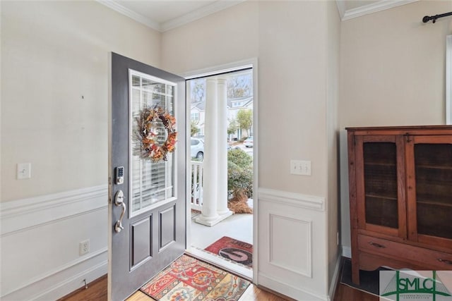 foyer entrance featuring wood-type flooring, ornamental molding, and decorative columns