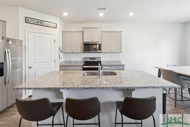 kitchen with a kitchen island with sink, gray cabinetry, and appliances with stainless steel finishes