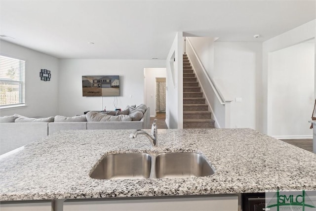 kitchen with hardwood / wood-style flooring, light stone countertops, and sink